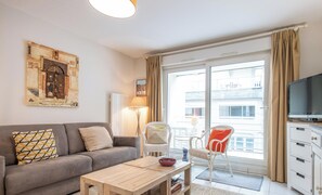 Ein Wohnzimmer mit einer Couch, einem Couchtisch, einem Fernseher und einem Balkon mit Blick.