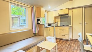 Une cuisine compacte avec des meubles en bois, une cuisinière encastrée et une fenêtre donnant sur les arbres.