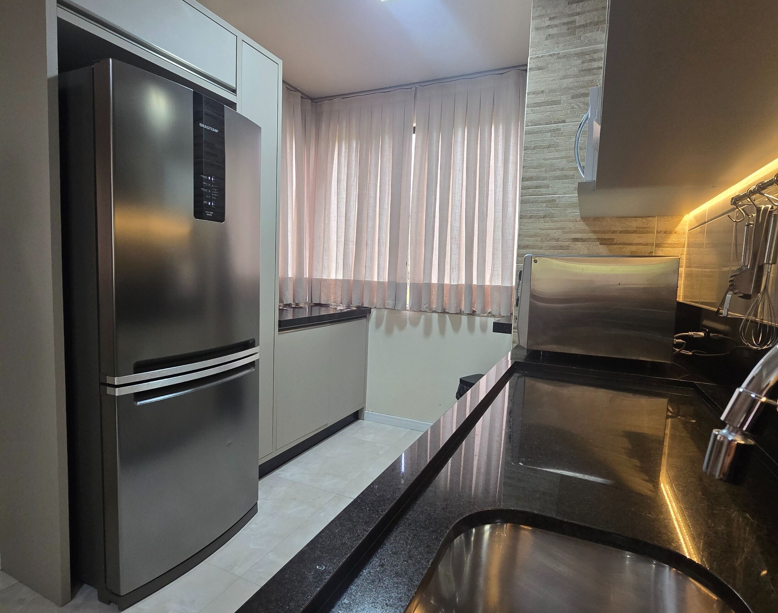 A modern kitchen with a stainless steel refrigerator, a built-in oven, and a sleek countertop.