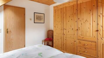 Quarto com cama, guarda-roupa de madeira e uma cadeira.