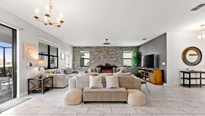 Ein geräumiges Wohnzimmer mit einem großen, beigefarbenen Ecksofa, einem Kamin und einem Fernseher.