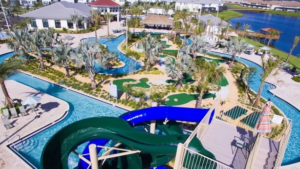 Ein Wasserpark mit einer großen Wasserrutsche, mehreren Pools und Palmen.