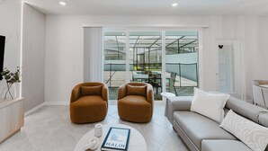 Una sala moderna con dos sillones marrones, un sofá gris y una mesita de centro con un libro.
