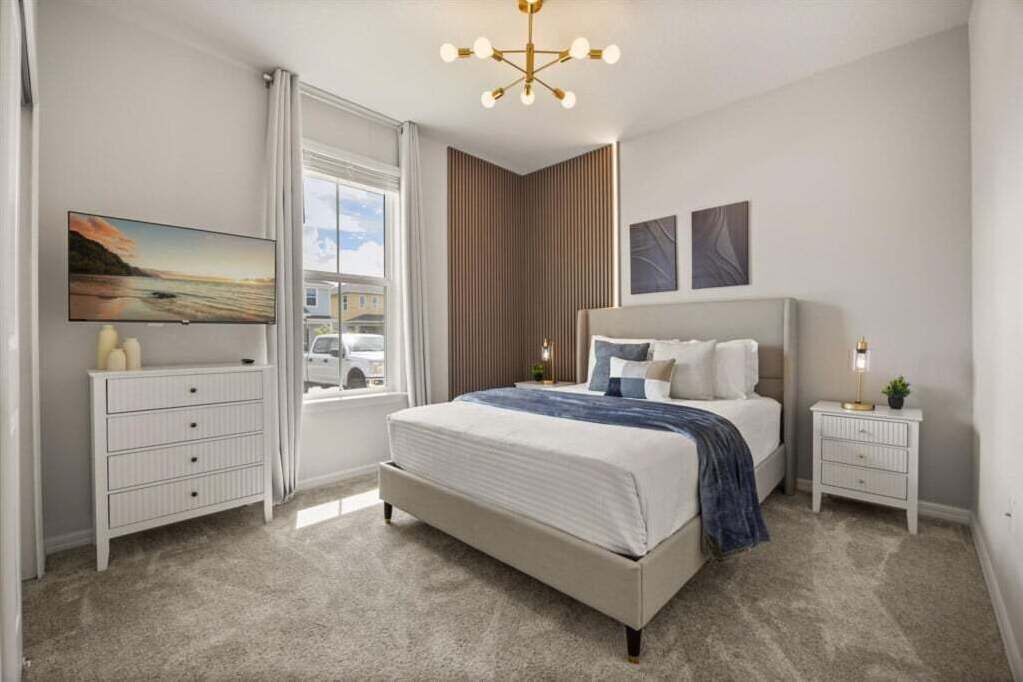 Une chambre moderne avec un grand lit, une table de chevet, une télévision et une fenêtre avec des rideaux.