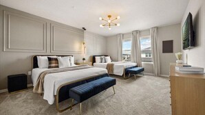 Une chambre d’hôtel avec deux lits, une grande fenêtre, un téléviseur à écran plat et un bureau avec une lampe.