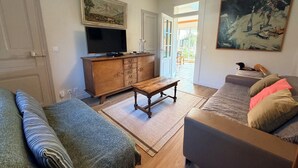 A living room with a television, wooden cabinet, bench, and two sofas.