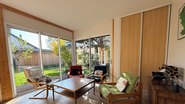 A spacious room with a sliding glass door leading to a backyard, a wooden table, and two chairs.