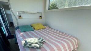 Une petite chambre à coucher, de taille réduite, avec un lit, une fenêtre et un plancher en bois.