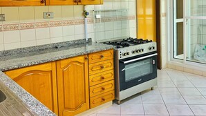 Une cuisine avec des meubles en bois, un plan de travail en granit, une cuisinière à gaz et un four.