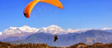 A person paragliding with a mountain range in the background.