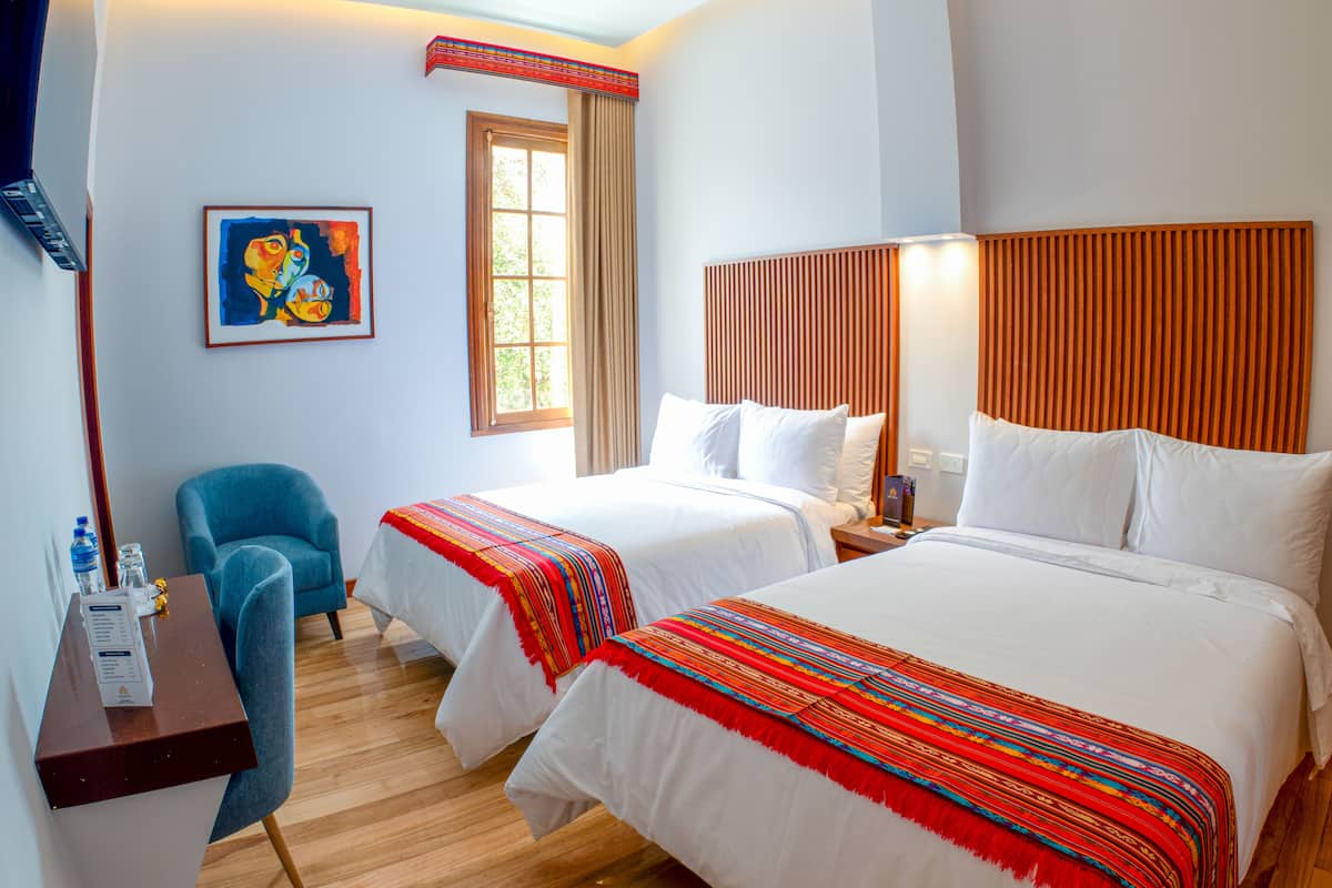 Een hotelkamer met twee bedden, een bureau met stoel, een raam met gordijnen en een schilderij aan de muur.
