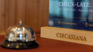 Un mostrador de recepción con un cartel que indica un cargo adicional de 25 dólares por llegada tardía.
