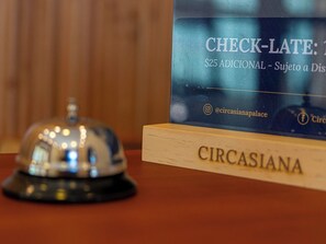 Un mostrador de recepción con un cartel que indica un cargo adicional de 25 dólares por llegada tardía.
