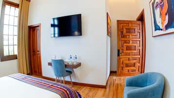 Una habitación de hotel con una cama, un escritorio con una silla, un televisor y una puerta con un diseño geométrico.