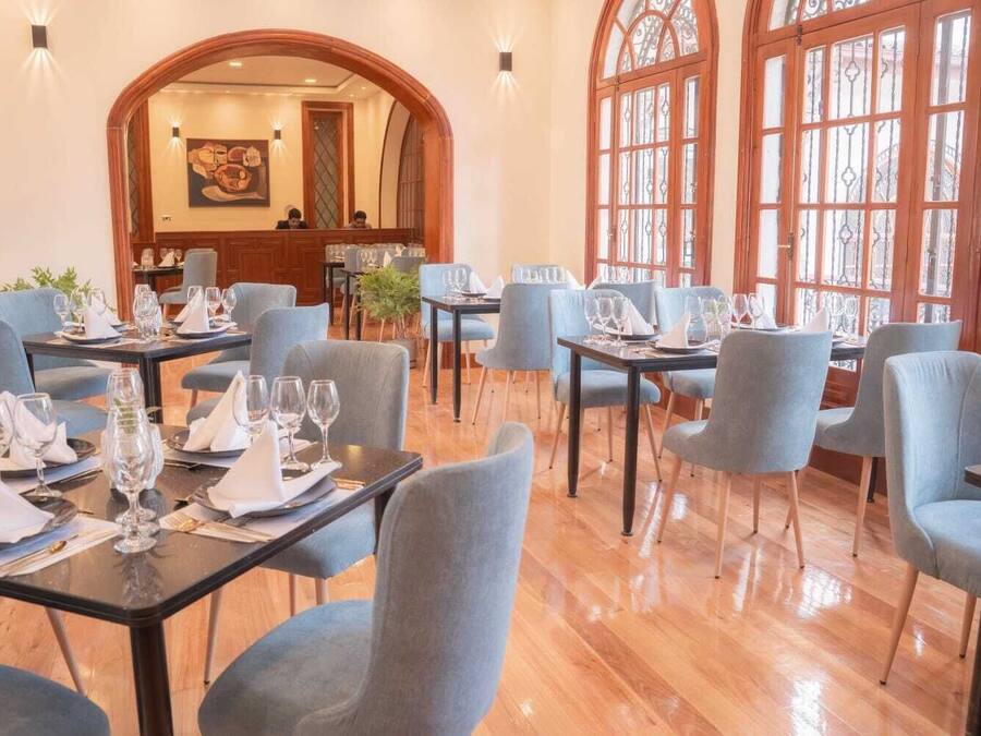 Ein Restaurant mit mehreren Tischen und Stühlen, Holzböden und großen Fenstern.