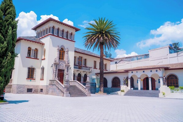 Un edificio histórico con un patio central, una palmera y una escalera que conduce a la entrada.