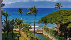 Vista costiera con palme, una spiaggia e un ponte che conduce a un elemento d'acqua.