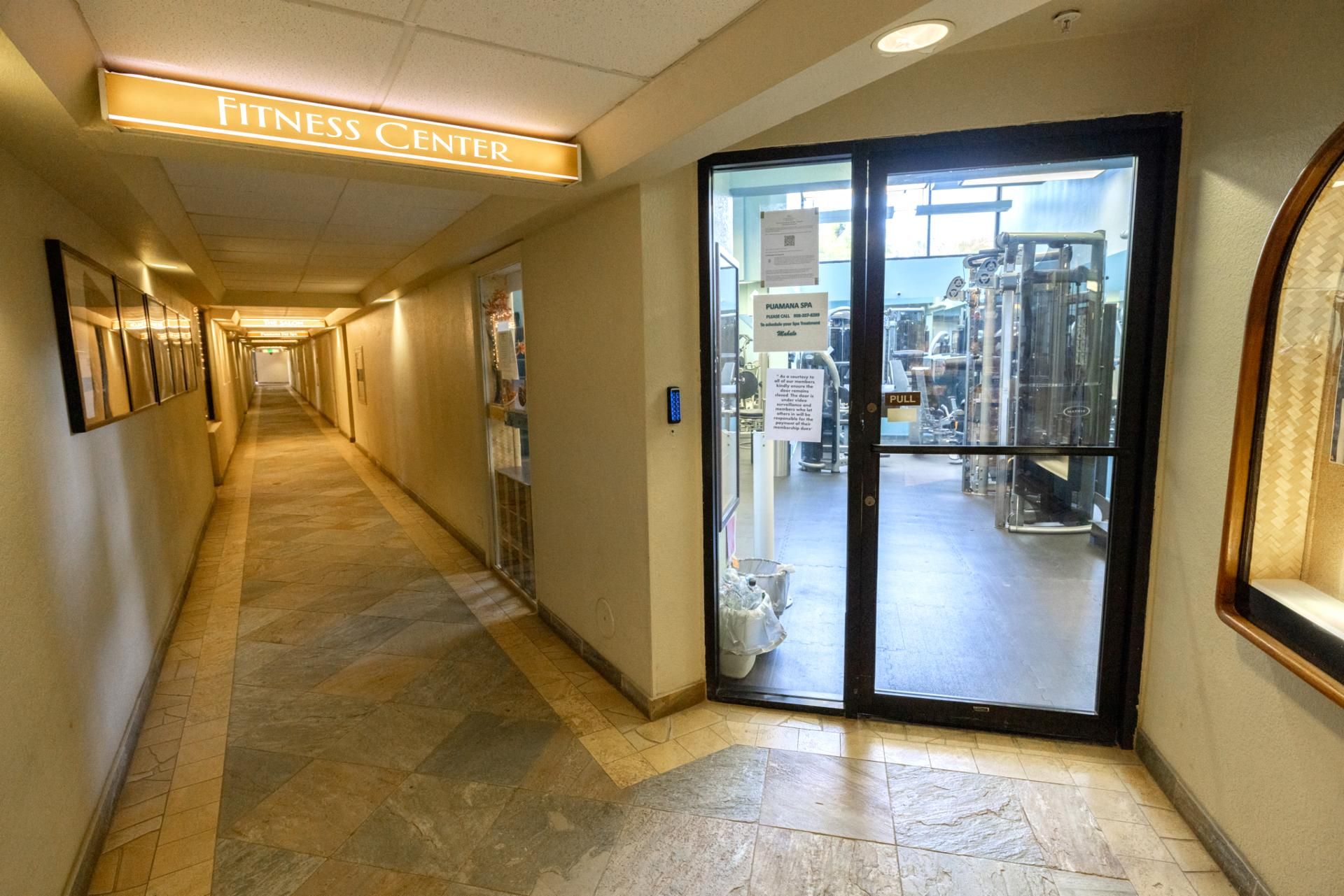 Un couloir menant à une salle de sport, avec une enseigne au-dessus de la porte.