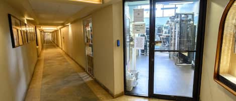 Un couloir menant à une salle de sport, avec une enseigne au-dessus de la porte.