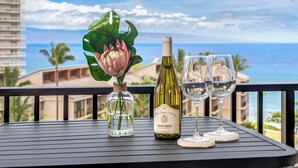 Un tavolo con una bottiglia di vino, due bicchieri e un vaso con un fiore.
