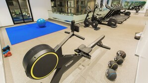 Ett gym med träningsredskap, en blå matta och hantlar.