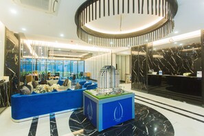 Eine moderne Lobby mit einer blauen Sitzecke, einem Modellbau und einer Rezeption.