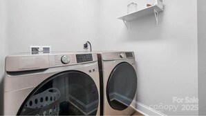 Eine Samsung Waschmaschine und ein Trockner in einem Waschraum mit weißer Wand und einer kleinen Ablage.