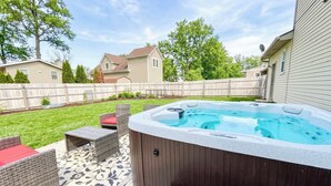A backyard with a hot tub, wicker furniture, and a wooden deck. - 4 BR - Hot Tub-Game Room-Near MGM-Sleeps 8 (Northfield)