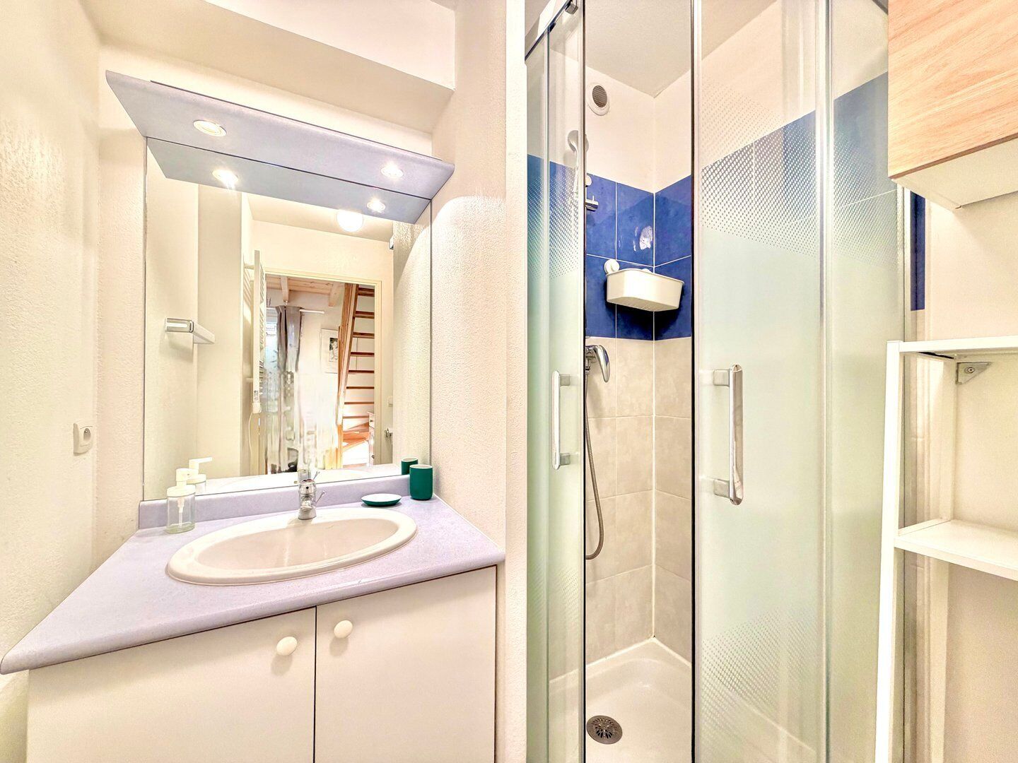 A modern bathroom with a glass-enclosed shower, a vanity with a sink, and a mirror above the sink.