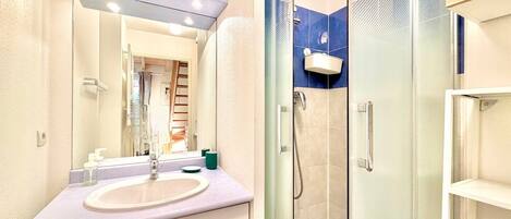 A modern bathroom with a glass-enclosed shower, a vanity with a sink, and a mirror above the sink.
