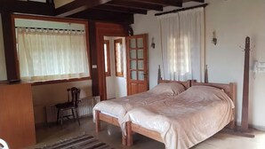Une chambre à coucher avec un lit double, un bureau en bois, une chaise et un radiateur.