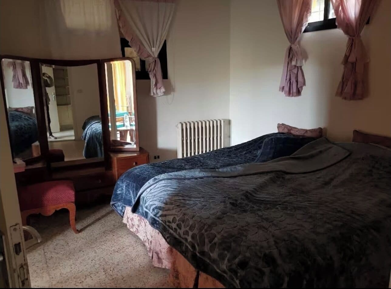 A bedroom with a bed, a dresser, a mirror, and a radiator.