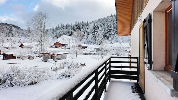 A snowy landscape with houses and a wooden building with a balcony. - Chez Valentin (Gérardmer)