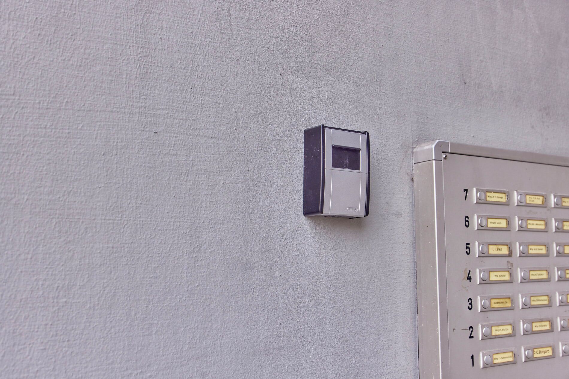 Un clavier doté de touches numérotées et un petit appareil électronique fixé sur un mur texturé.