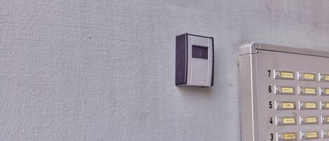 Un clavier doté de touches numérotées et un petit appareil électronique fixé sur un mur texturé.