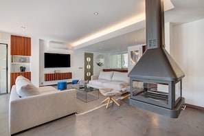 Een moderne woonkamer met een bank, salontafel en een grote open haard.