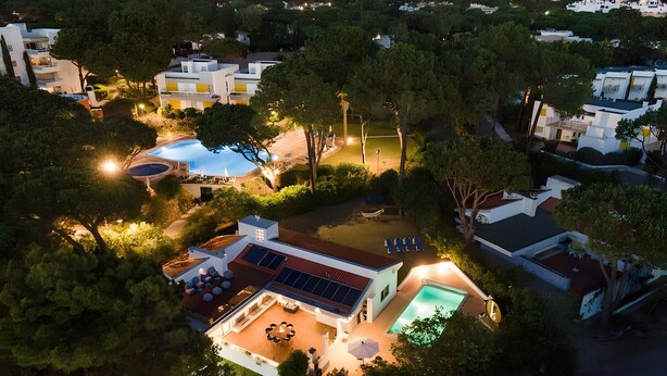 Un quartier résidentiel avec des maisons modernes, une piscine et un espace patio aménagé avec du mobilier d’extérieur.