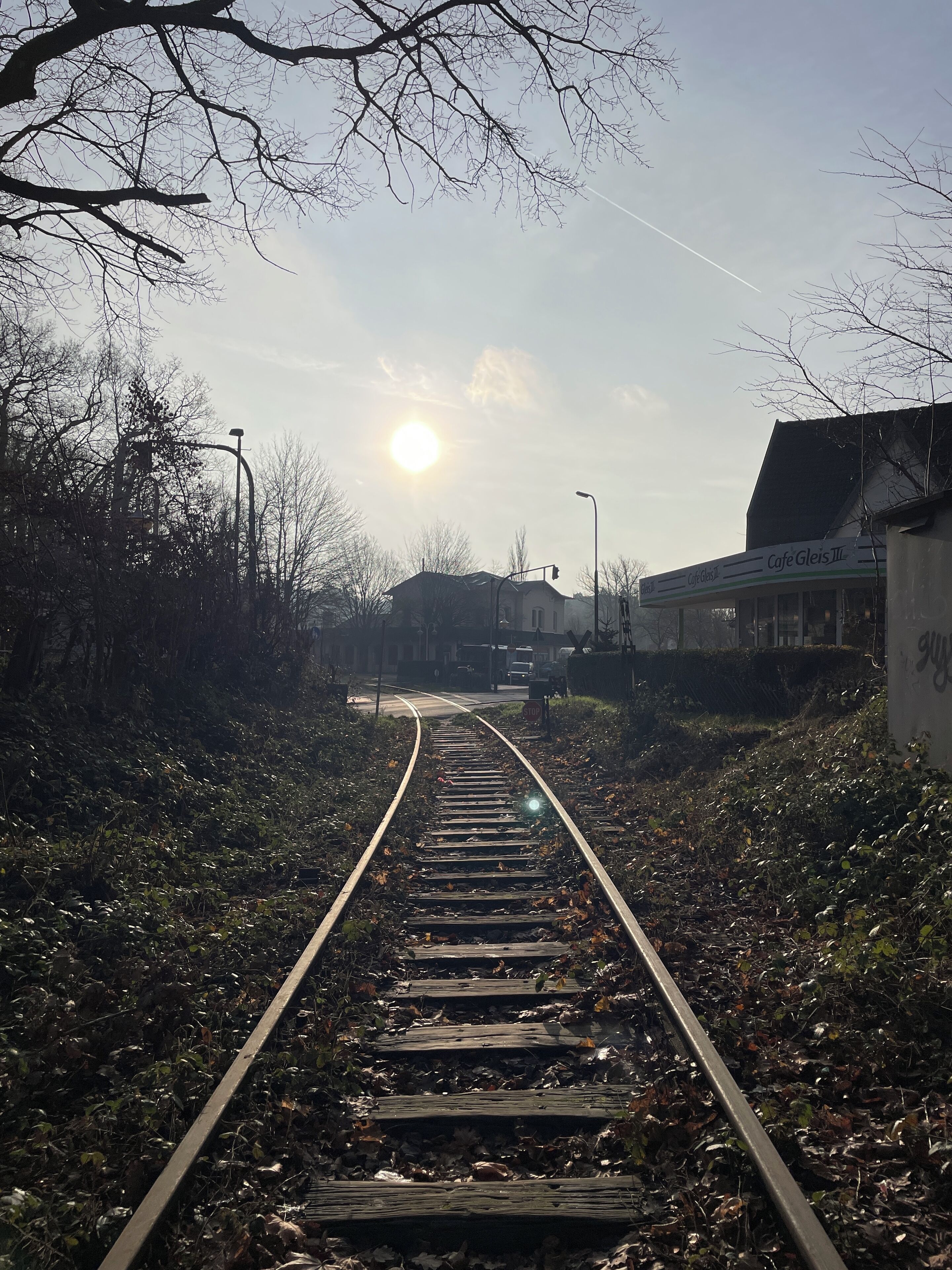 Une voie ferrée avec un bâtiment portant l’inscription « Café Gleis III » sur la droite.