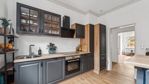 Une cuisine moderne avec des meubles gris, un plan de travail en bois et un four encastré.