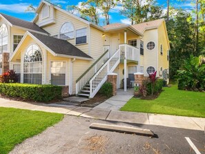 A two-story building with a central staircase, a covered porch, and a well-maintained lawn. - Resort Pool*Renovated*Near Parks! (Kissimmee)