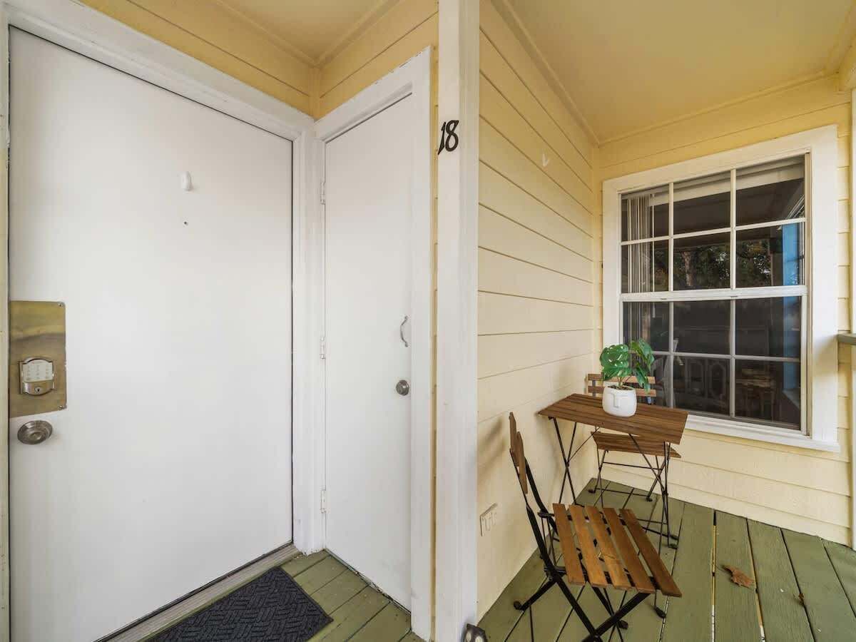 A door with a number '18' on the wall, a window with blinds, and a small table with a plant.