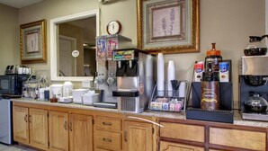 A kitchen with wooden cabinets, a microwave, a coffee machine, and various kitchen appliances. - Oak Tree Inn (Durant)