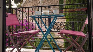 Un balcon donnant sur un bâtiment historique en pierre, doté d’une tour avec une horloge.