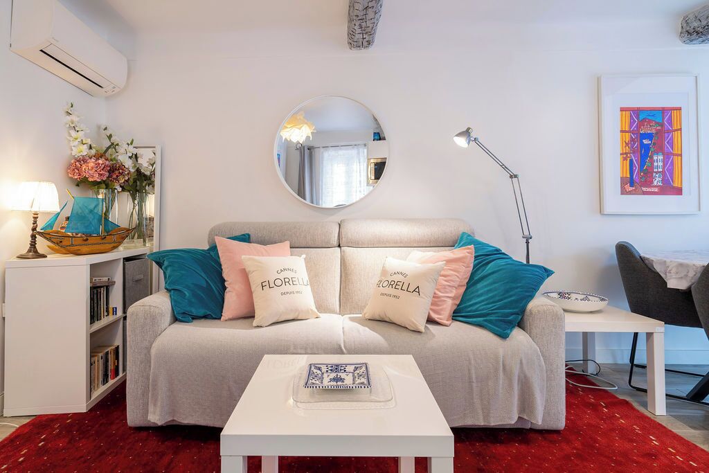 En moderne stue med sofa, rundt spejl, sofabord og reol.
