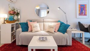 Un salon moderne avec un canapé, un miroir rond, une table d’appoint et une bibliothèque.