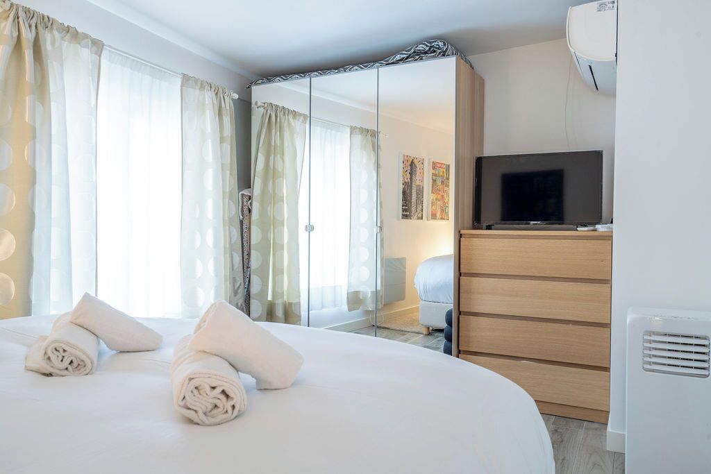 A hotel room with a large bed, a TV, a wardrobe, and a mirror.