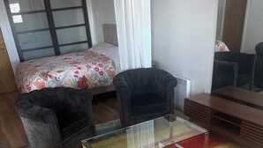A living room with a glass coffee table, two armchairs, a sofa, and a colorful striped rug.