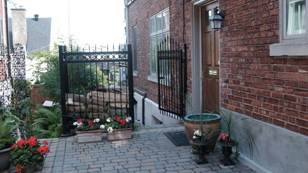 A brick building with a gated entrance, potted plants, and a brick pathway.