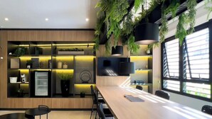 A modern kitchen with built-in appliances, wooden cabinetry, and a dining area with a table and chairs. - Update Vila Madalena by Wecare Hosting (São Paulo)