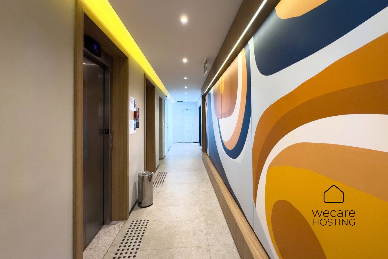 Un couloir d’hôtel au design moderne, avec un mur orné de motifs et une poubelle.
